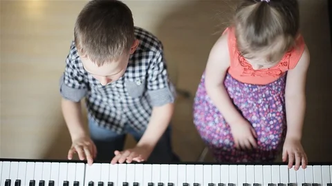 Top view of two children playing in their room on a synthesizer. Stock Footage 98858761
