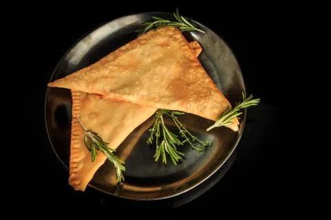 Top view of two fried triangles of chebureki with green rosemary Stock Photos