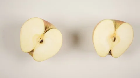 TOP VIEW: Two half of an apple are swinging on a white table Stock Footage