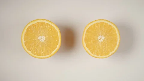 TOP VIEW: Two half of an orange are swinging on a white table Видео 73294763