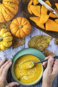 Top view of two hands with spoon of an unrecognizable man eating pumpkin soup Stock Photos