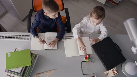 Top view. The two little brothers sit at the desk at home and draw drawings Stock Footage 84946199