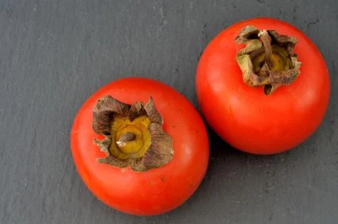 Top view of two persimmons on a slate plate Stock Photos