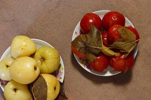 Top view of two plates filled with pickled apples and pickled tomatoes. Stock Photos