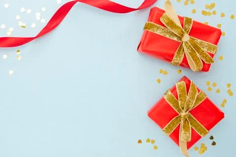 Top view of two red gift boxes with golden sparkling ribbon and golden confet Stock-Fotos