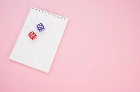 Top view of two rolling dices on a notebook isolated on a pink background Stock Photos
