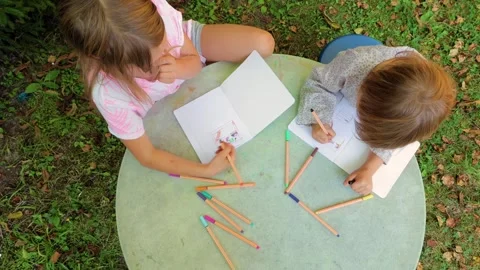 Top view of two sisters drawing with fineliners in notebooks in a summer gard Stock Footage 304327674
