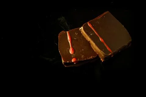 Top view of two small square chocolate candies on black background Stock Photos