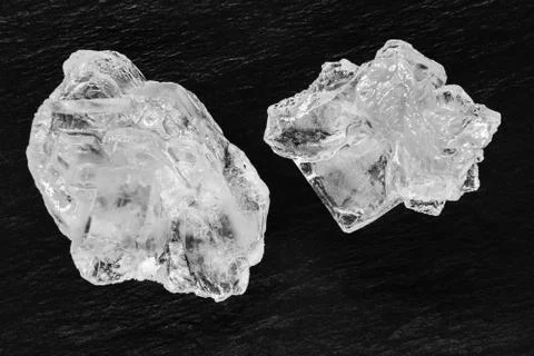 Top view of two sugar or salt crystals placed on black stone background surfa Stock Photos