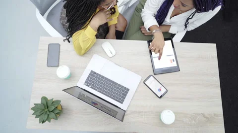 Top view of two young black women working in the office. Reviewing analytical Stock Footage 148669949