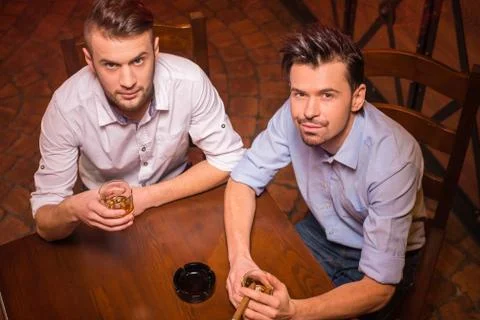 Top view of two young men in shirt with beer while sitting together at the bar c Stock Photos