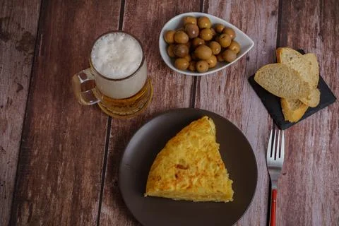 Top view of typical spanish potato omelette with bread, cutlery and beer mug Stock Photos