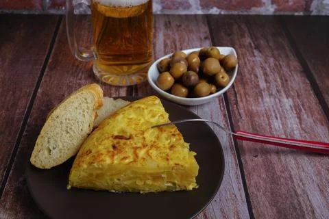 Top view of typical spanish potato omelette with bread, cutlery and beer mug Stock Photos