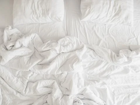 Top view of unmade bedding sheets and pillow ,Unmade messy bed after comfort Stock Photos