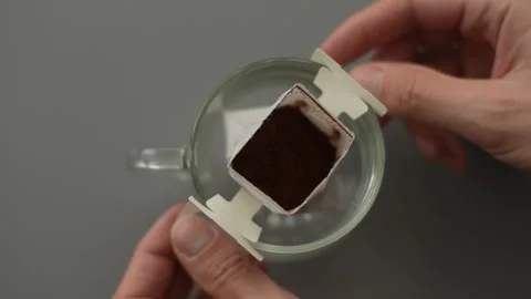 Top view of unrecognizable man carefully placing drip coffee bag into clear Stock Footage 297624237