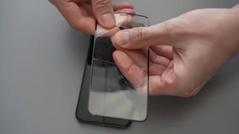 Top view of unrecognizable technician removing broken tempered glass screen Stock Footage 297632544