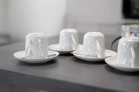 Top view of upside down white porcelain mugs on saucers on kitchen table Stock Photos