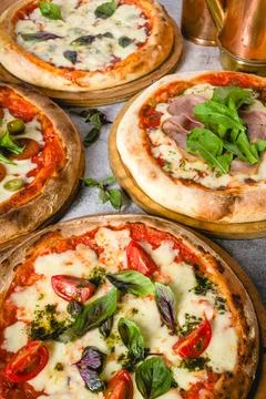 Top view of various neapolitan pizzas on grey stone table Stock Photos