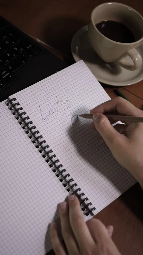 Top view vertical video of person writing "Let's go" in notepad near coffee cup Video stock 344058147