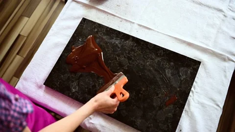 Top view video with a chocolatier tempering melted liquid dark chocolate on a ma Stock Footage 154555888
