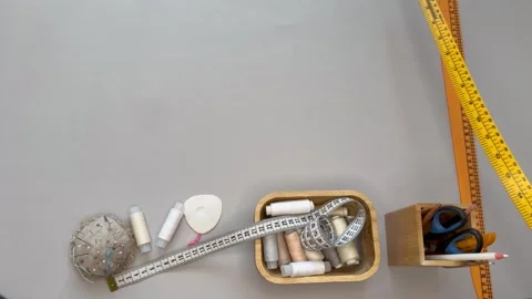 Top view video of cutting table. Seamstress lays out sewing accessories, fabrics Stock Footage 306561086