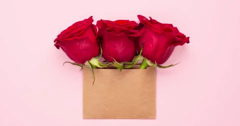 Top view video scale of three bright red rose flowers in brown craft envelope Stock Footage 276448465