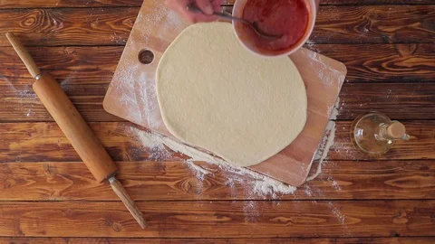 Top view video of woman is adding tomato sauce to pizza base Stock Footage 90089051