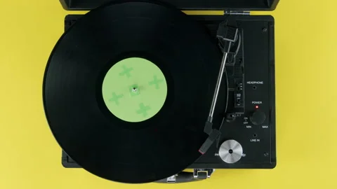 Top view of vinyl on record player on yellow background and green label Stock Footage 218630336