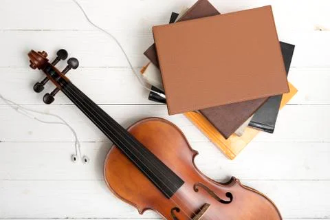 Top view of violin with stack of book and earphone Stock Photos