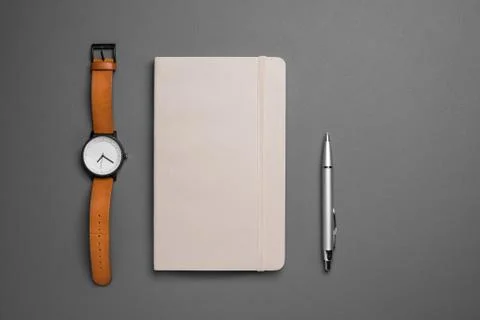 Top view of watch and notebook with pen on grey background Stock Photos