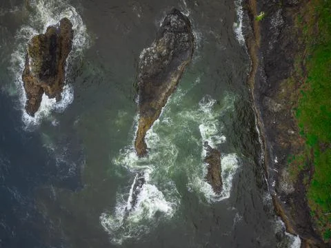 Top view of the water surface with large boulders in the water and a hilly gr Stock Photos