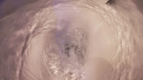 Top view of water swirling down a white ceramic toilet bowl during a powerful Stock Footage 332272132