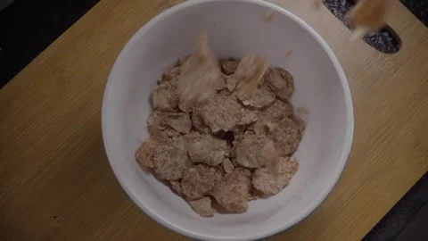 Top view of wheat cereal flakes served in white bowl on wooden table for Stock Footage 343710267