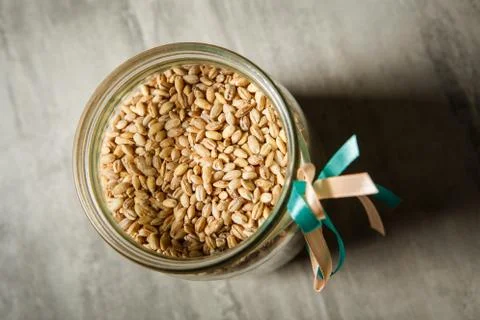 Top view of wheat seeds in opened glass jar decorated with white and blue rib Stock Photos