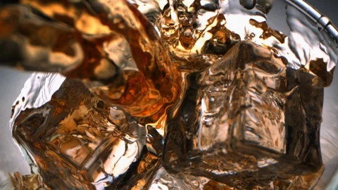 Top View of Whiskey Pouring with a Flow inside a Glass with Ice Cubes Vidéo 124210824