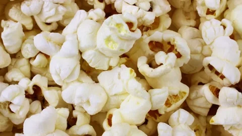 Top view of white and yellow fresh salted popcorn falling down with rotation Stock Footage 233998077