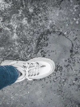 Top view of white boot on icy ground near melting water puddle. Urban sprin.. Stock Photos
