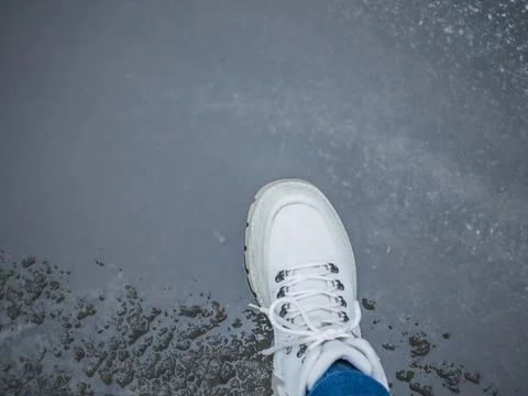 Top view of white boot stepping on wet slushy ground. Concept of spring tha.. Stock Photos