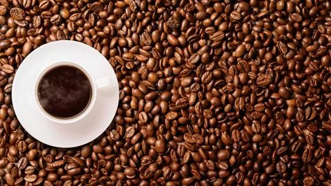 Top view of a white ceramic cup filled with hot black coffee, placed on a d.. 写真素材