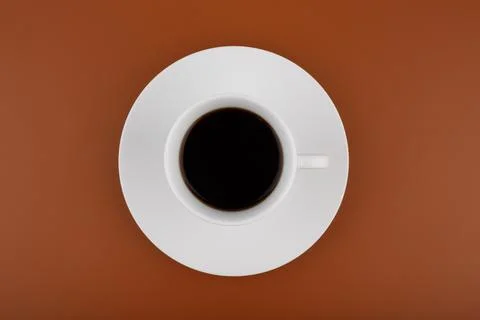 Top view of white coffee cup on a table against brown background Stock Photos