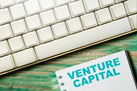 Top view of a white computer keyboard and a notebook with 'VENTURE CAPITAL'.. Stock Photos