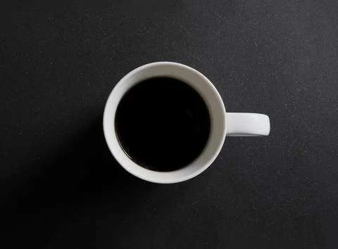 Top view of a white cup of coffee on black granite counter Stock Photos