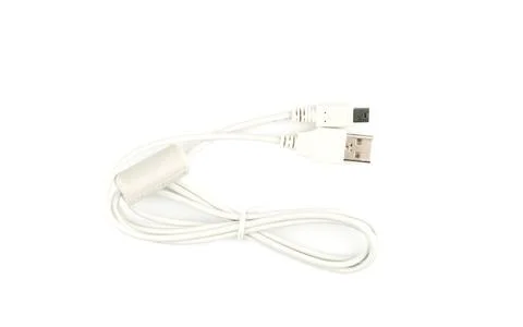 Top view of a white data cable with a ferrite filter and USB connectors. Stock Photos