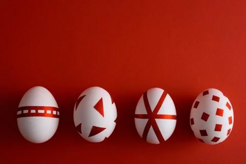 Top view white Easter eggs decorated with shiny red stickers on red matte bac Stock Photos
