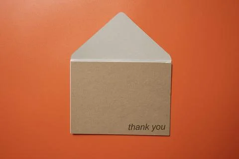 Top view of white envelope and postcard with brown card with words "Thank Y.. Stock Photos