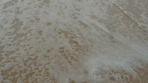 Top View of White Ocean Foam Rushing over Sandy Beach in Slow Motion, Close-up Stockbeeldmateriaal 335713156