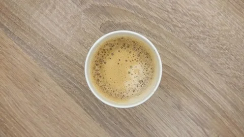 Top view of white paper disposable Irish coffee cup with foam on a wooden table Stock Footage 263245726
