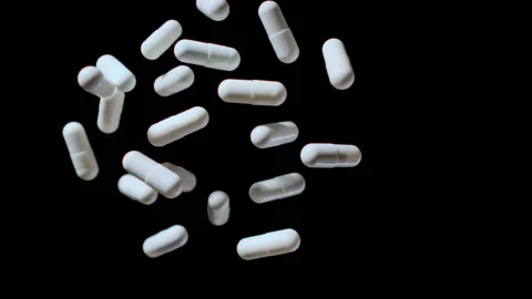 TOP VIEW: White Pills fly up and down on a black background, Slow motion Stock Footage 149543391