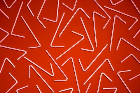 Top view of white plastic straws on red color background creating pattern Stock Photos