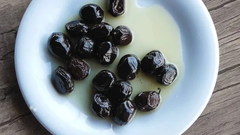 Top View Of White Plate With Black Olives In Oil On A Wooden Table Stock Footage 195979432